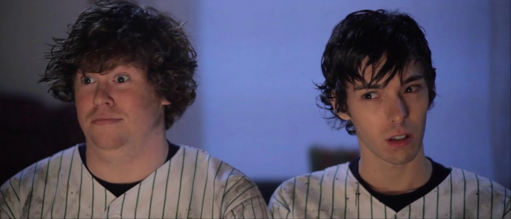 Scene from Hot Bot movie starring Zack Pearlman and Doug Hailey.  They looked stunned and suspicious respectively.  Both are wearing white baseball jerseys with dark pin stripes.